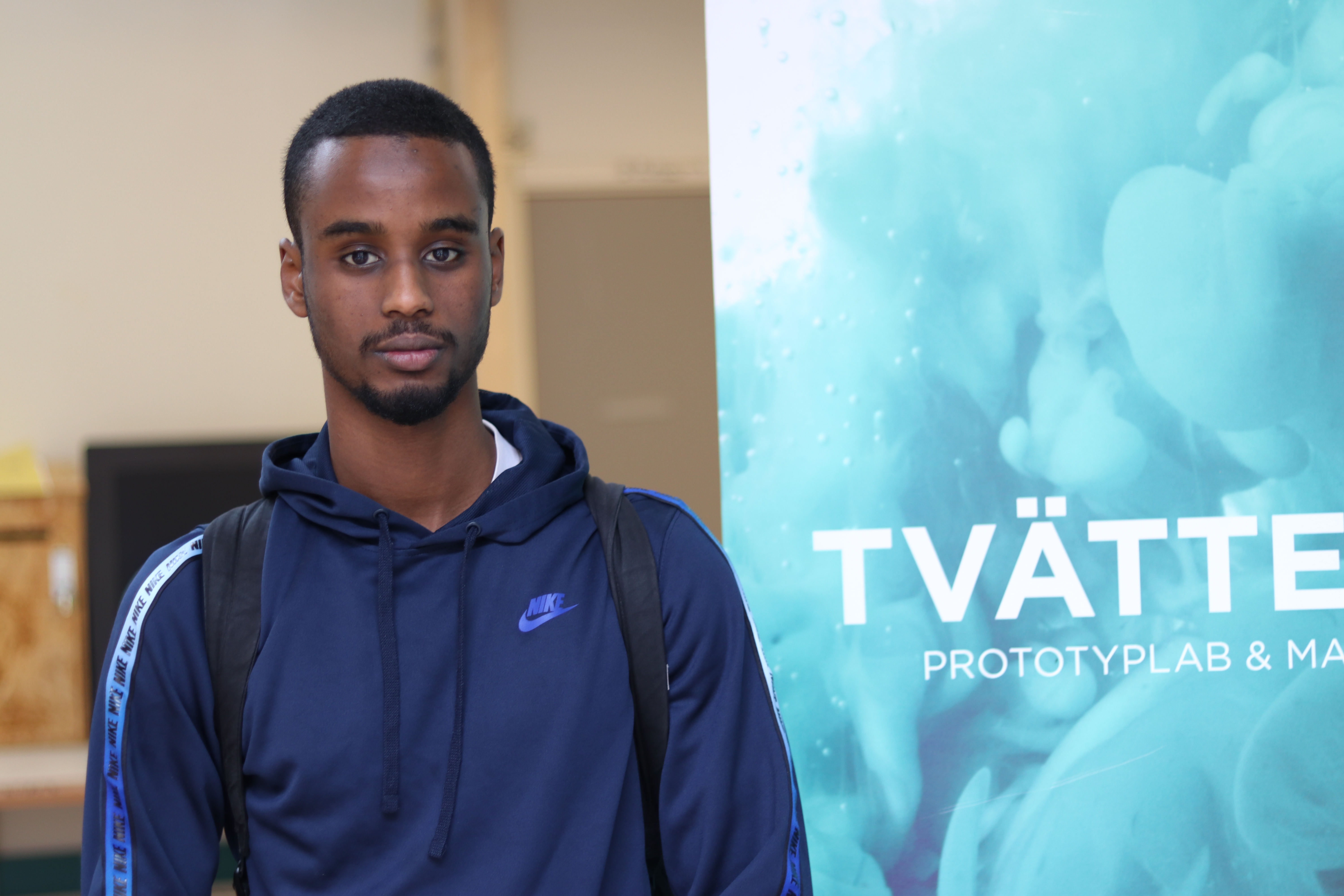 Kille i blå hoodie står framför en rollup