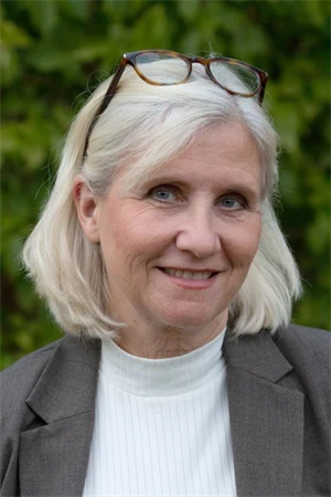 En kvinna utomhus i vit tröja och grå kavaj