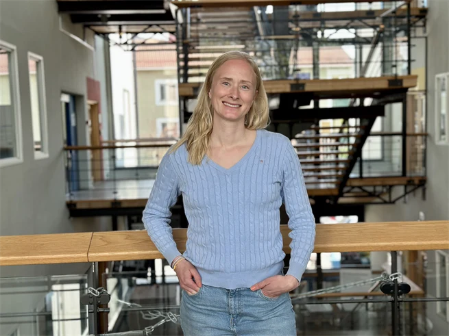 Amanda Mattsson, en kvinna i ljusblå tröja framför en trappa