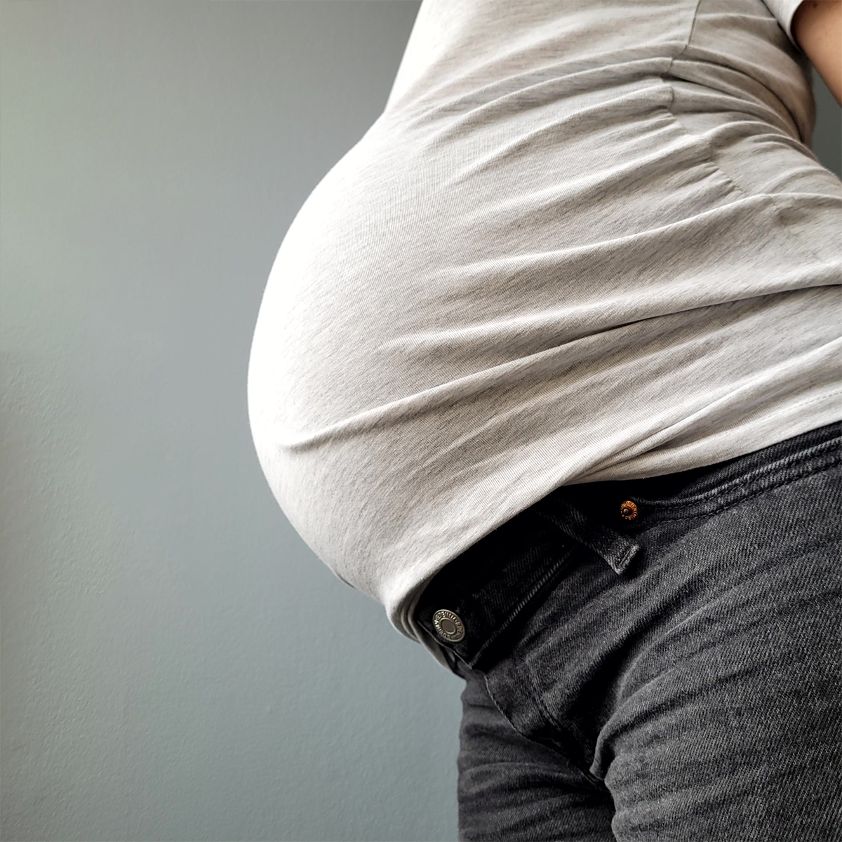 Pregnant woman shows belly.