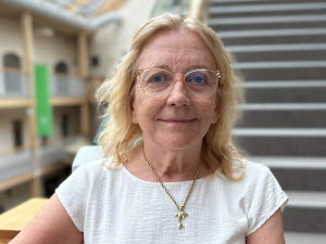 Porträttfoto av en blond kvinna ståendes framför en trappa
