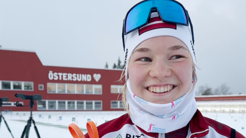 Leende kvinna på skidskyttestadion.